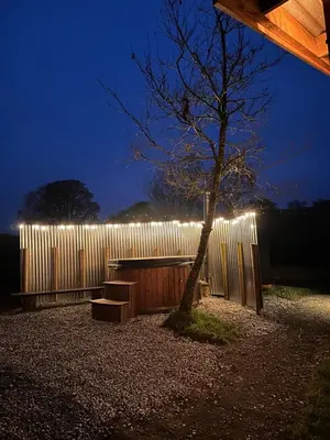a tree and a bench in front of a fence at Woolly Wood Cabins - Bryn in Llandrindod Wells