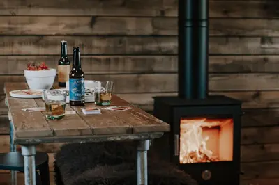 a table with two bottles and glasses next to a stove at Woolly Wood Cabins - Bryn in Llandrindod Wells
