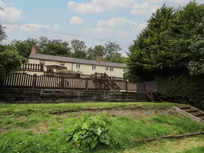 a white house with a fence and a garden at Bluebell's Cottage in Shrewsbury
