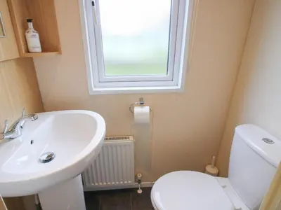 a bathroom with a sink and a toilet and a window at Dove in Leominster
