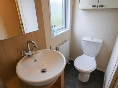 a bathroom with a sink and a toilet and a window at Dove in Leominster