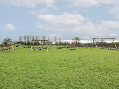 an empty park with swings in a grassy field at Dove in Leominster