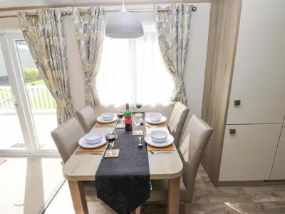 a dining room with a table and chairs and a window at 116 Woodpecker Lodge in New Quay