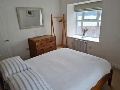 a bedroom with a bed and a dresser and a window at No.1 Sail House in New Quay