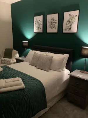 a bedroom with a large bed with a green wall at The Old Coach House in Llangollen