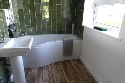 a bathroom with a tub and a sink and a window at The Old Coach House in Llangollen