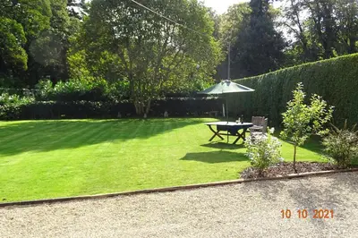 a lawn with a picnic table and an umbrella at The Old Coach House in Llangollen