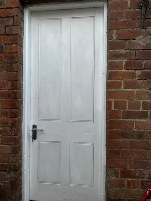 a white door in a brick wall at Flat 2 The Butlers Quarters in Oswestry