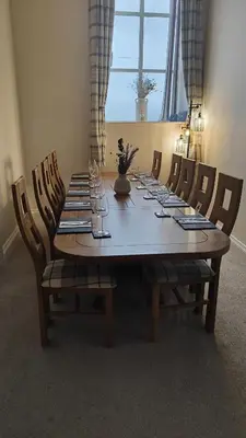 a wooden table with chairs and a large table with wine glasses at 1 Chapel Nazareth in Penrhyndeudreath