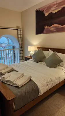 a bedroom with a large bed with white sheets at 1 Chapel Nazareth in Penrhyndeudreath