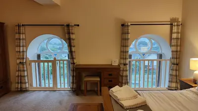a bedroom with two large arched windows and a bed at 1 Chapel Nazareth in Penrhyndeudreath