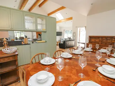 a dining room with a wooden table with glasses on it at The Coach House at Plas Dolguog in Machynlleth