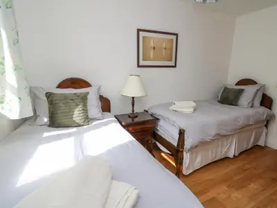 a bedroom with two beds and a lamp on a table at The Coach House at Plas Dolguog in Machynlleth