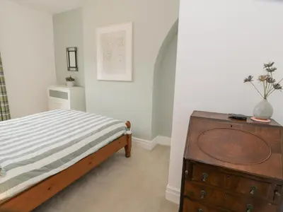 a bedroom with a bed and a wooden dresser at Swn Yr Afon in Tywyn