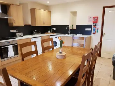 a kitchen with a wooden table and a dining room at Peregrine Stable Cottage in Llandovery
