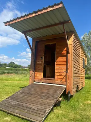a wooden outhouse with a porch in a field at Ox Box Cabin Lyonshall Kington in Hereford