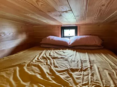 a large bed in a wooden cabin with a window at Beaver Tail Cabin in Hereford