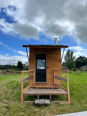a tiny house with a deck in a field at Beaver Tail Cabin in Hereford