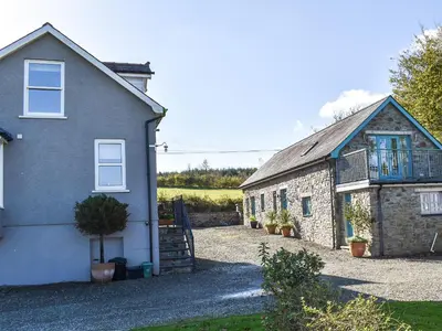 a stone house and a building with a balcony at Cartws Blaenparc Coach House - Uk41031 in Mydroilin