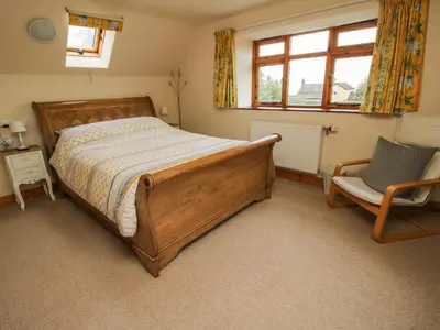 a bedroom with a bed and a chair and a window at Rowan Cottage in Shrewsbury