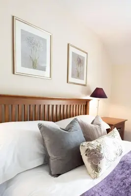 a bed with a wooden headboard and two pictures on the wall at Penuwch Fach in Aberystwyth