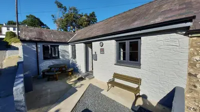 a small white building with a bench in front of it at No 1 Dolheulog Aberaeron SA46 0EP in Aberaeron