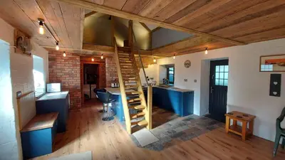 a living room with a staircase in a room with a kitchen at No 1 Dolheulog Aberaeron SA46 0EP in Aberaeron