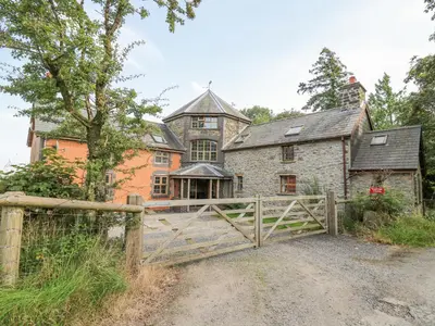 an old stone house with a gate in front of it at Nanthir House in Llandrindod Wells