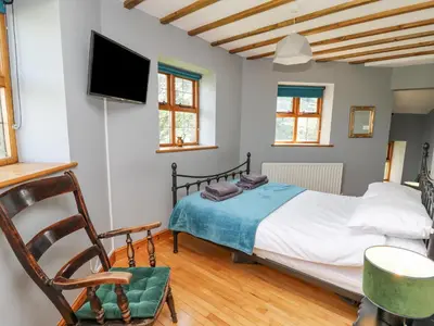 a bedroom with a bed and a tv on the wall at Nanthir House in Llandrindod Wells