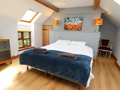 a bedroom with a large bed with a blue blanket at Nanthir House in Llandrindod Wells