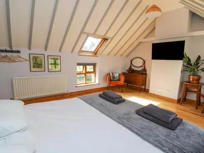 a bedroom with a large white bed and a television at Nanthir House in Llandrindod Wells