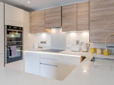 a kitchen with white counter tops and wooden cabinets at Contemporary Apartment with Secure Parking - Pass the Keys in Shrewsbury
