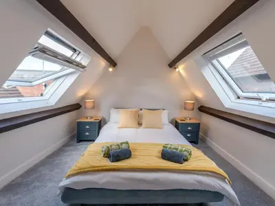 a bedroom with a large bed and two windows at Dahlia Contemporary town centre apartment - Pass the Keys in Shrewsbury