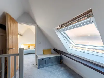 a small attic room with a window and a bench at Dahlia Contemporary town centre apartment - Pass the Keys in Shrewsbury