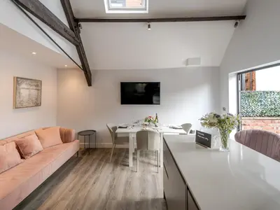 a kitchen and living room with a couch and a table at Dahlia Contemporary town centre apartment - Pass the Keys in Shrewsbury