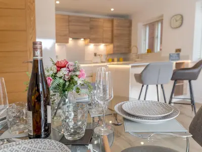 a bottle of wine sitting on a glass table with flowers at 1 bed Albury Contemporary Apartment with Secure Parking - Pass the Keys in Shrewsbury