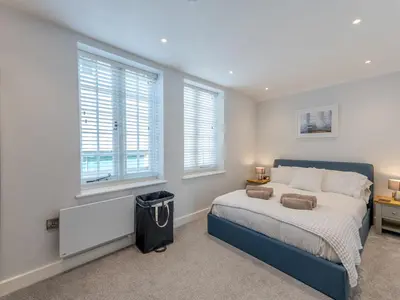 a bedroom with a large bed and two windows at 1 bed 40D Dahlia Contemporary town centre apartment - Pass the Keys in Shrewsbury