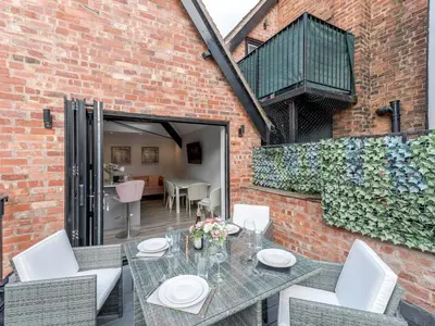 a patio with a table and chairs and a brick wall at 1 bed 40D Dahlia Contemporary town centre apartment - Pass the Keys in Shrewsbury