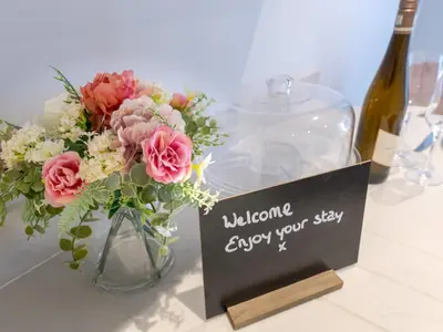 a vase with flowers and a sign that says welcome enjoy your stay at Bouvardia Modern town centre apartment - Pass the Keys in Shrewsbury