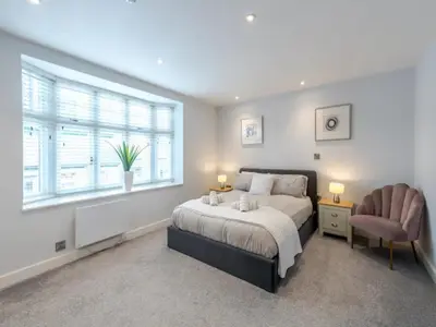 a bedroom with a bed and a chair and a window at Bouvardia Modern town centre apartment - Pass the Keys in Shrewsbury