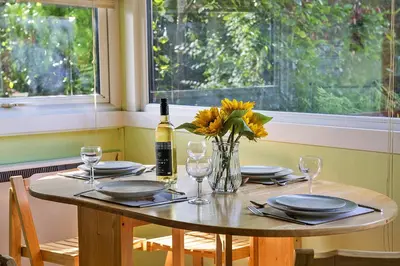 a table with a bottle of wine and a vase of flowers at Finest Retreats - Mountain View in Trawsfynydd