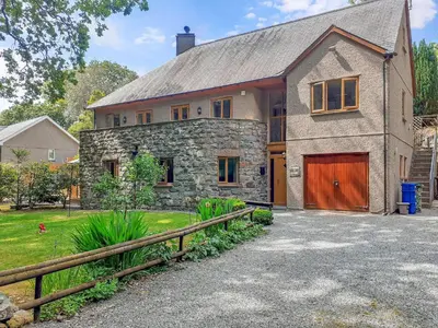 a large stone house with a wooden garage at Cysgod Y Coed in Llanbedr