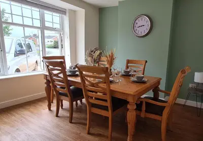a dining room table with chairs and a clock on the wall at Cosy yet spacious, 3BR, Parking, Village Location in Oswestry