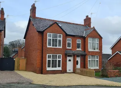 a red brick house with a white door at Cosy yet spacious, 3BR, Parking, Village Location in Oswestry