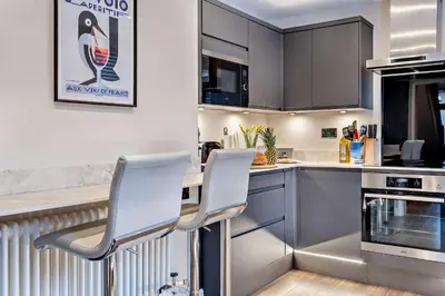 a kitchen with two white chairs and a counter at Shrewsbury Townhouse - Free Parking in Shrewsbury