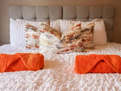 a white bed with pillows and orange towels on it at Mynydd Y Glyn Lodge in Llanfyllin