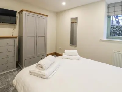 a bedroom with a large white bed with towels on it at The Barn by Lyons in Talybont