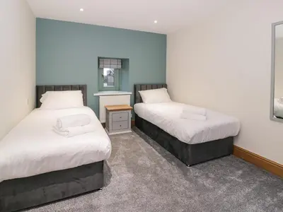 a bedroom with two beds and a mirror at The Barn by Lyons in Talybont