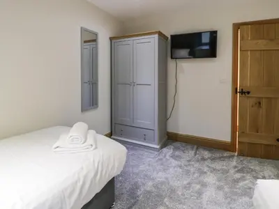a bedroom with a bed and a tv and a closet at The Barn by Lyons in Talybont
