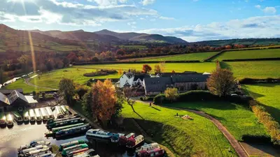 an aerial view of a house and a river with boats at Dragonfly Cottage, Canal location in Brecon